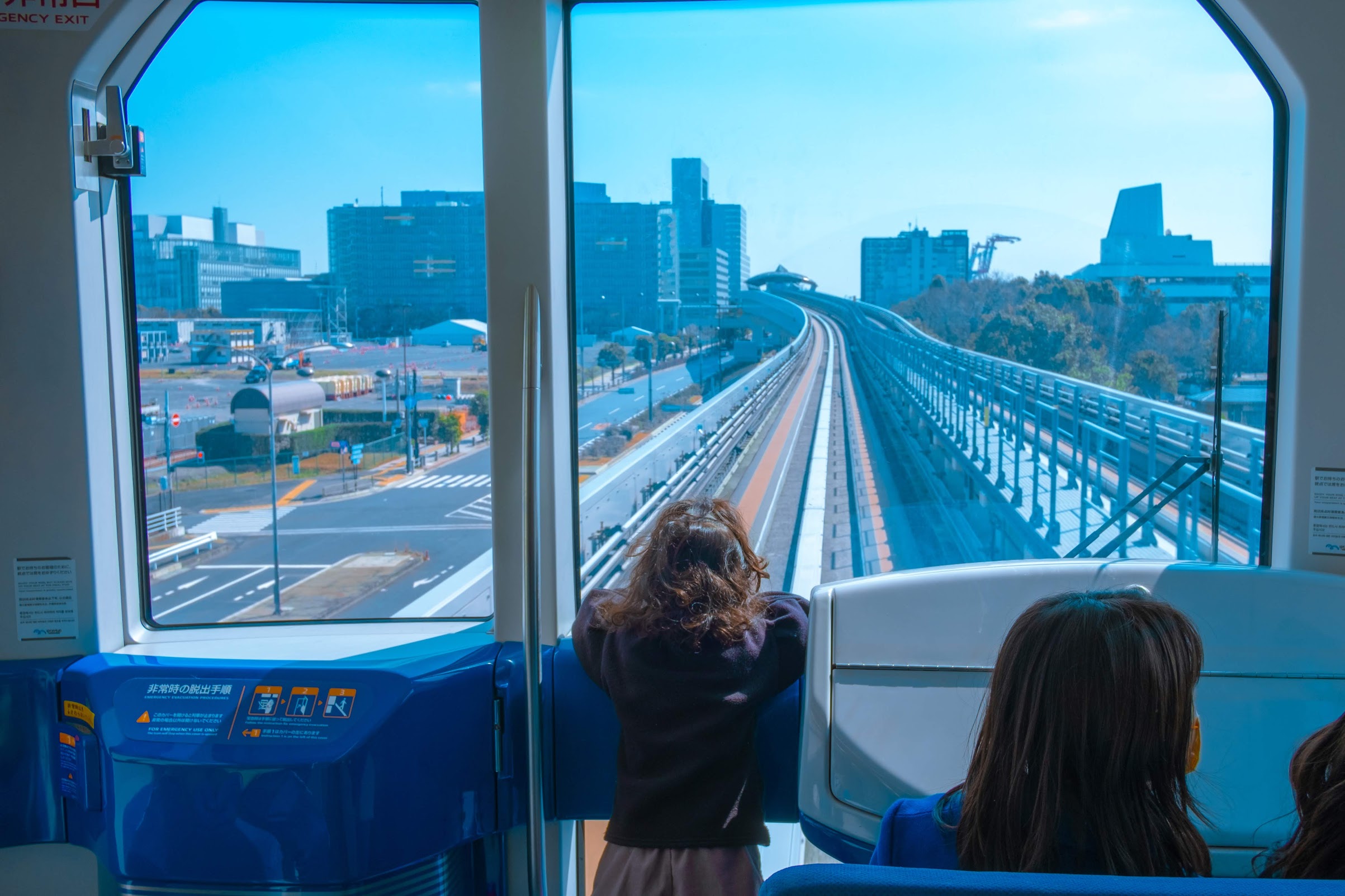 Ein kleines Mädchen blickt aus der großen Glasfront einer selbstfahrenden japanischen Metro.