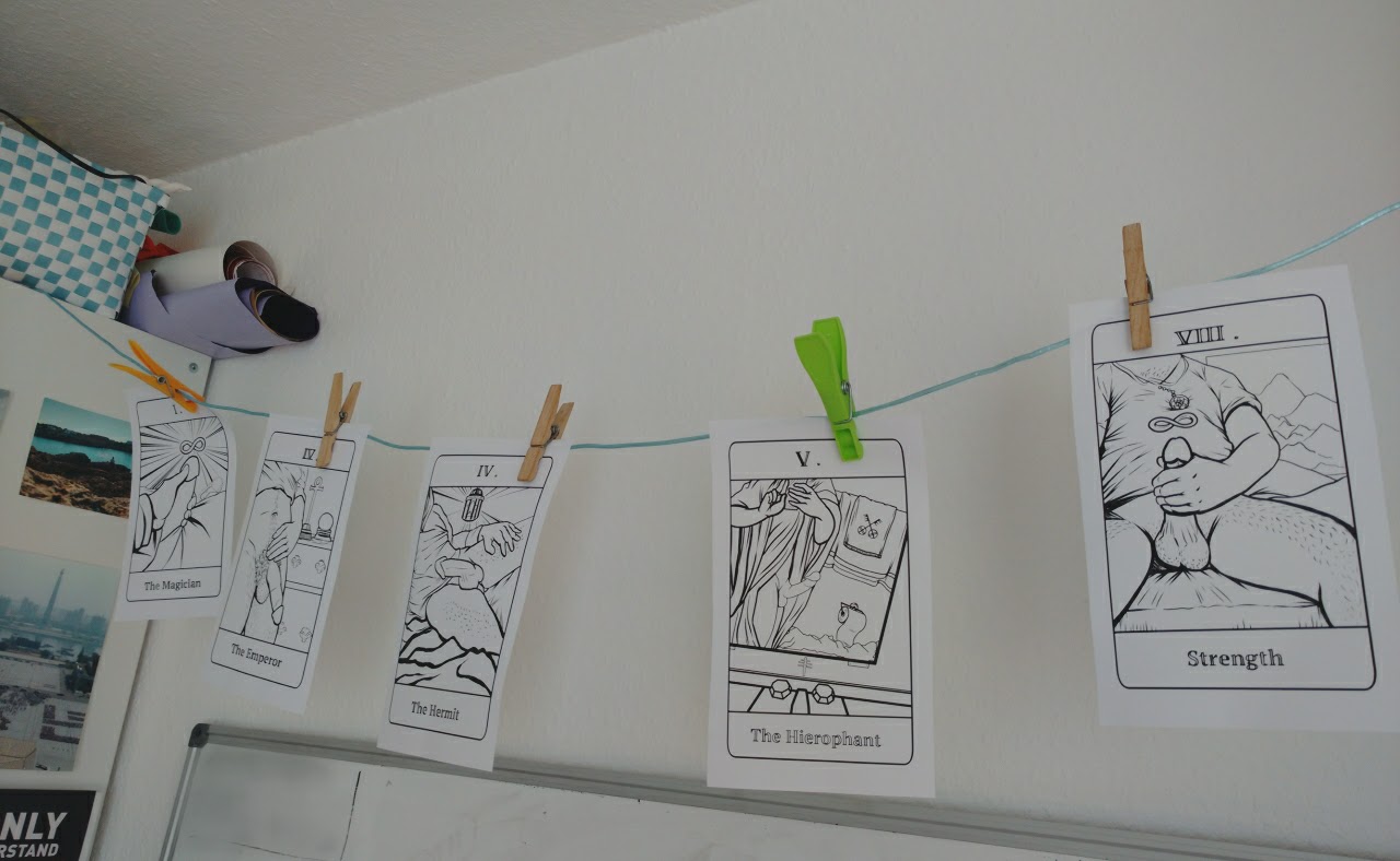 Auf einer Wäscheleine, hängen jeweils mit einer Wäscheklammer befestigt, Zeichnungen von Penisbildern als Tarot-Karten.