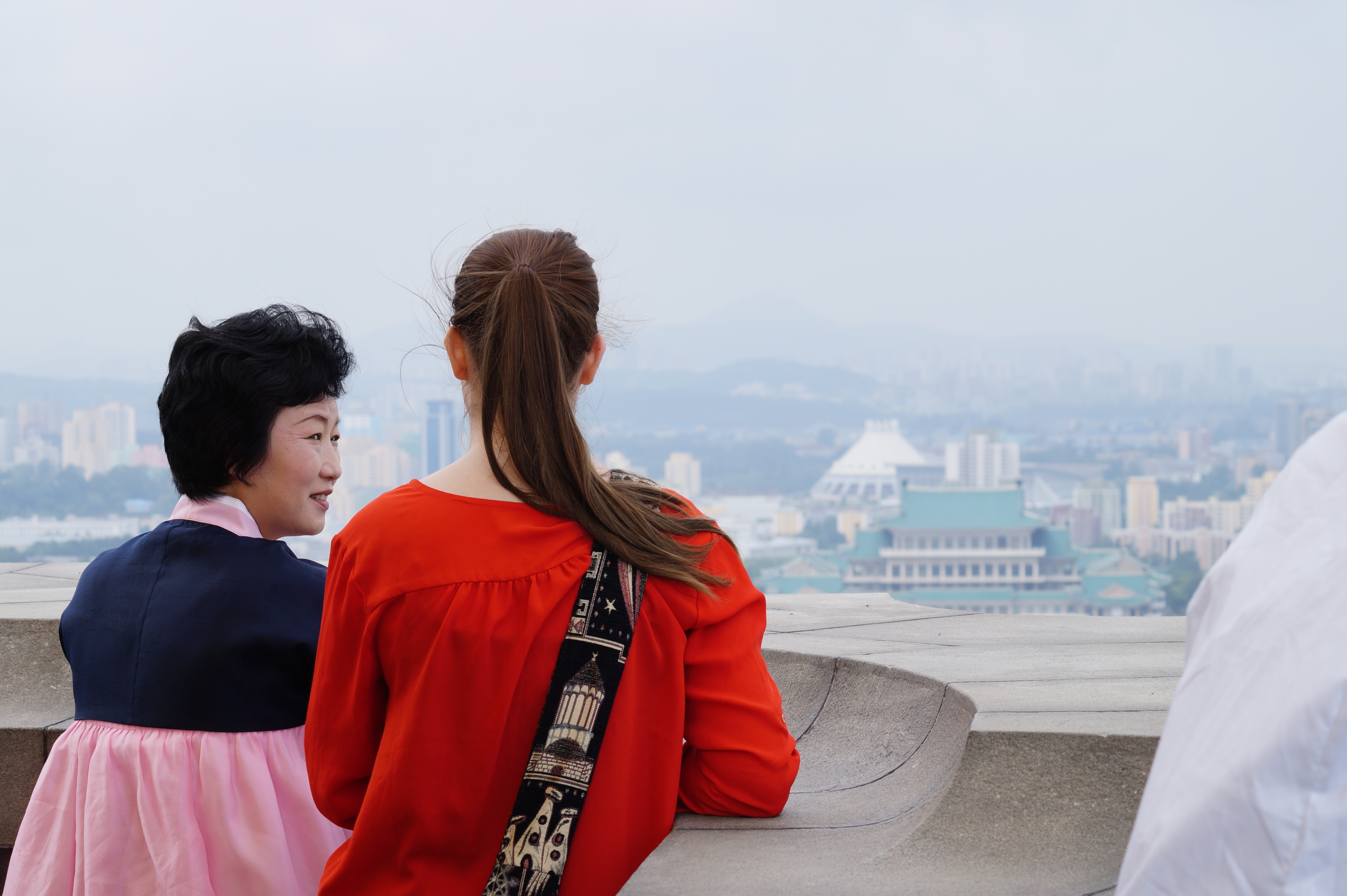 Gemeinsam neben einer Frau in traditionellen nordkoreanischen Gewändern stehe ich auf einem Turm und schaue über Pjöngjang.